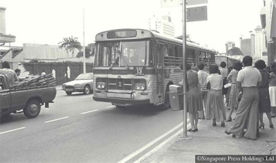 Passengers at a bus stop in the 1970s