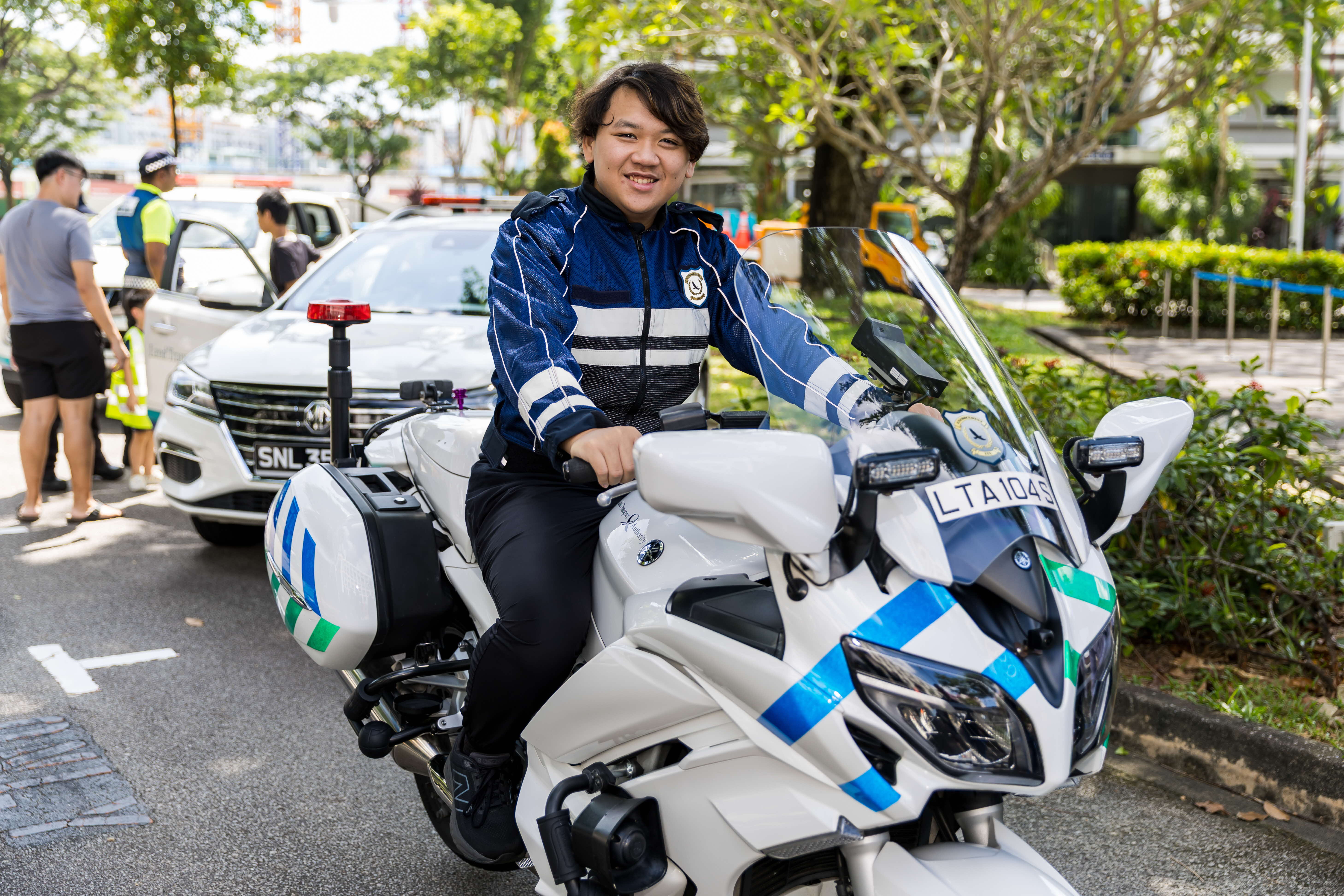 Image of FOLT Shan who is one of SGTrains’ young members. He is suited up in the Vehicle Enforcement Officer uniform and seated on an official enforcement patrol motorcycle used for daily operations.
